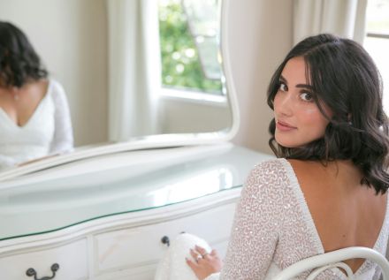 Confident young ethnic bride sitting near mirror before wedding ceremony